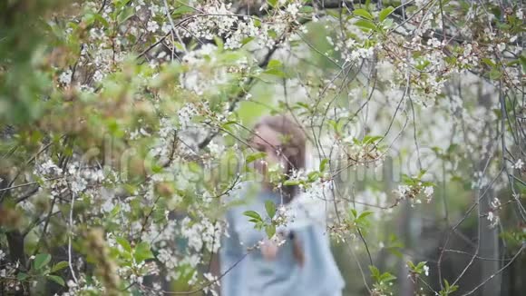 女孩跑着穿过樱花枝夏日慢动作视频的预览图