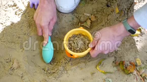 爸爸把沙子倒进玩具桶里沙箱男人帮助孩子视频的预览图
