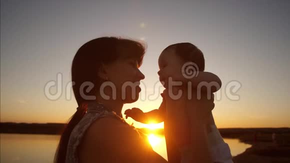 妈妈抱着小宝宝在金色的傍晚阳光的怀里慢动作视频的预览图