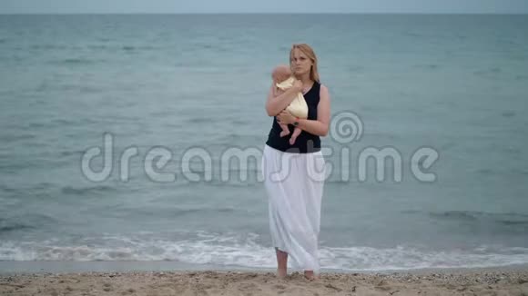母亲带着失落的神情抱着孩子独自在海边的海滩上视频的预览图