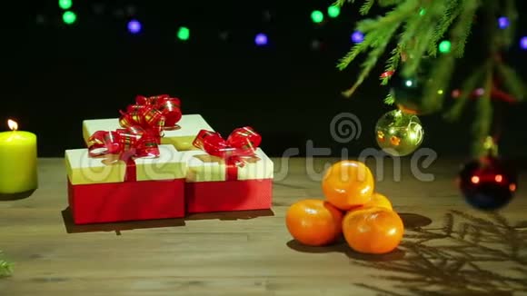 一个漂亮的盒子旁边有一棵圣诞树和一支燃烧的蜡烛放在黑色背景的木桌上视频的预览图