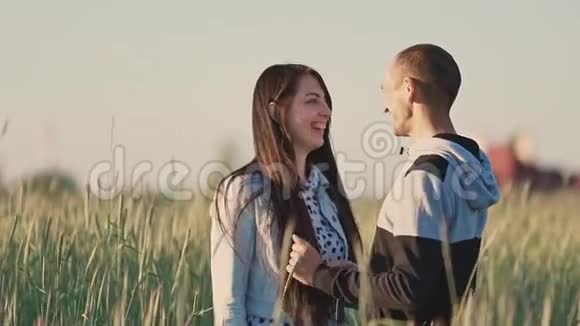 丈夫和妻子在一片麦田里在夕阳的余晖中他们互相拥抱接吻一起快乐视频的预览图