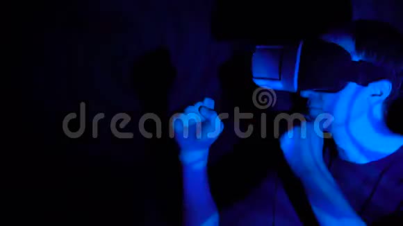 年轻帅哥在聚光灯下戴着虚拟现实头盔做武术动作视频的预览图