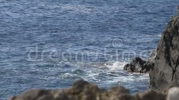 波涛汹涌的蓝海冲击着岩石悬崖从水中浮现缓慢的运动视频的预览图