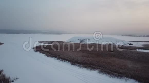 空中摄影冬天飞过土丘看到冰冻的河流和岸边的一座大山视频的预览图