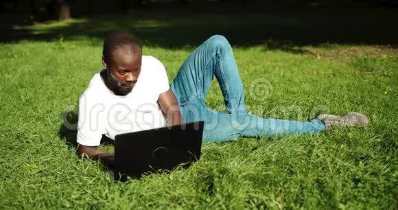 非裔美国人带着笔记本电脑在草地上视频的预览图