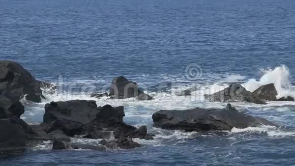 海浪冲击着从水中涌出的岩石造成泡沫飞溅视频的预览图