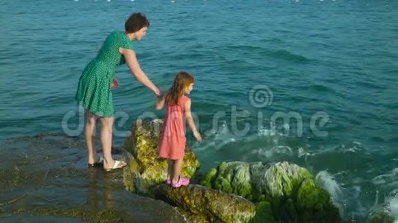 女人和女孩在岩石上波浪慢动作视频的预览图