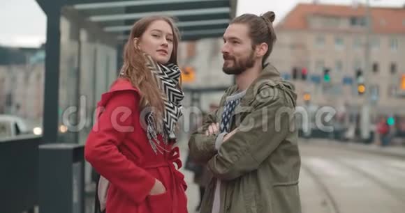 微笑的一对夫妇在一个城市的电车站等着看着远方视频的预览图