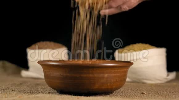 特写镜头一位老年妇女的双手从一堆谷物中倒入一个木盘子视频的预览图