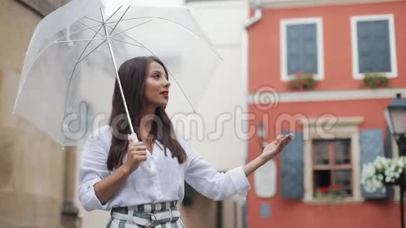 帅气的年轻女商人仰望天空举起手来检查雨是否停了她微笑着靠近视频的预览图