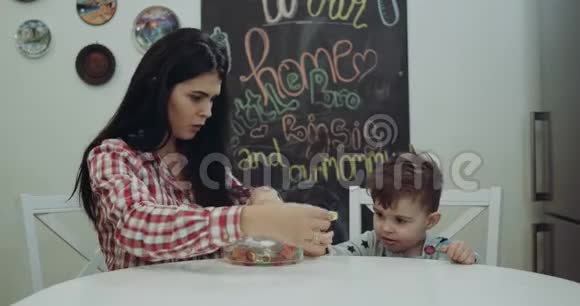 妈妈和她的孩子坐在厨房的椅子上玩果冻互相亲吻视频的预览图