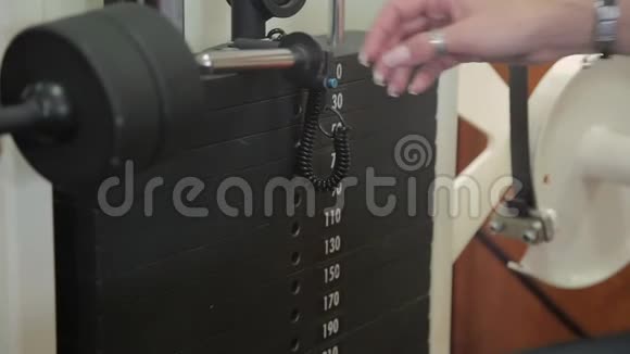 一个女孩用模拟器上的重量换吧台的特写健身那个女孩去参加体育活动视频的预览图