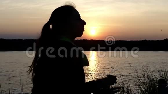 漂亮的女人坐在湖畔喝热水瓶里的茶视频的预览图