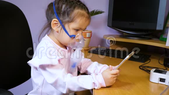 小可爱的女孩接受雾化器治疗并使用手机视频的预览图
