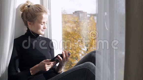 坐在窗台上看电子书的女人视频的预览图