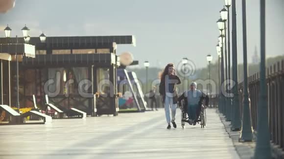 坐在轮椅上的残疾人在码头上和女朋友一起打电话视频的预览图