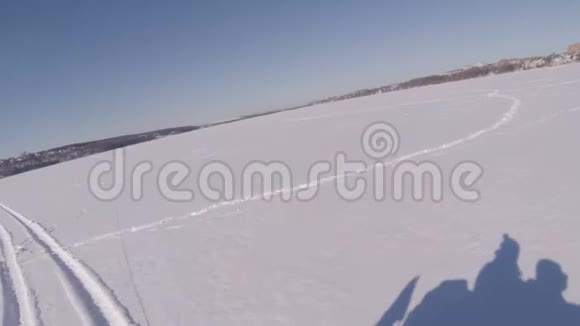 两个人在冰冻的湖面上骑着雪车在雪地里的人的影子视频的预览图