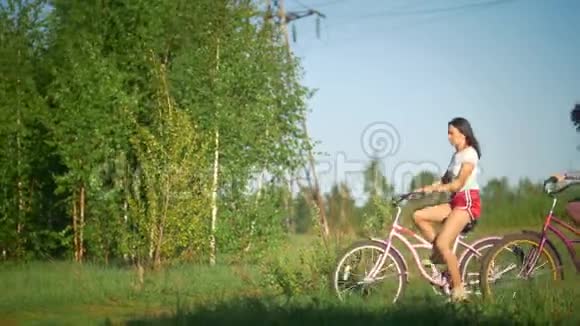 在公园阳光明媚的一天里绿树成荫的美丽女孩骑着自行车视频的预览图