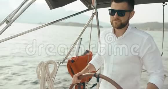 在游艇上的船长穿着白色衣服的长胡子帅哥双手握在游艇上的方向盘上视频的预览图