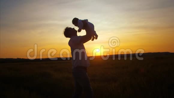 在金色的太阳落山时婴儿在他父亲的手中慢动作视频的预览图