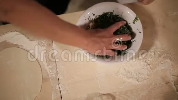 女性用手将切碎的草药放入擀面团中亚美尼亚披萨饼烘焙视频的预览图