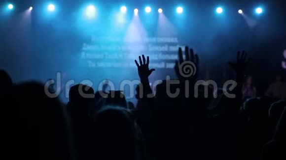 年轻人举起双手在音乐会上唱歌跳舞的剪影后视图视频的预览图