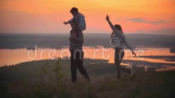妈妈和孩子用手展示飞机母亲和她的小儿子在猩红的夕阳下玩得很开心视频的预览图