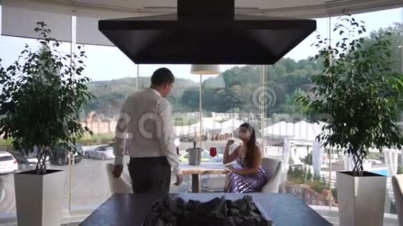 穿着西装的英俊自信的男人正走向他迷人的女士亲吻她的手坐在桌边浪漫的视频的预览图
