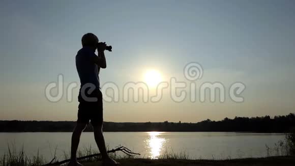 在斯洛莫的日落时分职业男子在湖面上拍摄一条灿烂的太阳道视频的预览图