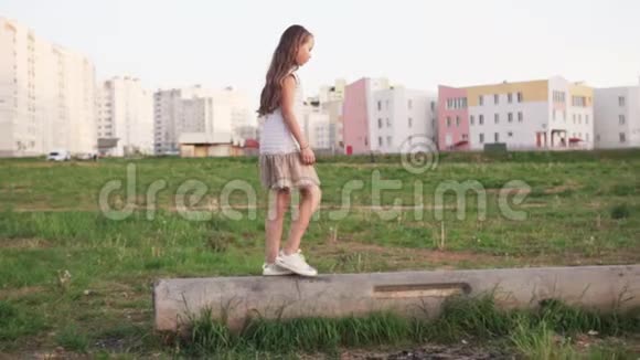 小女孩走在城市荒地上的水泥原木上视频的预览图