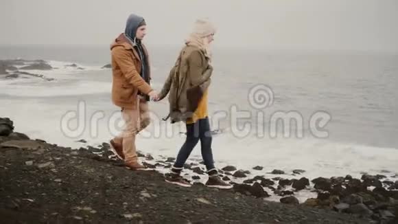在海边散步的年轻夫妇迷人的男人和女人在水边接吻视频的预览图