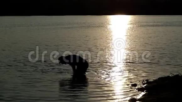 太阳落山时年轻人从湖里拿出一个冠军碗视频的预览图