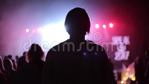 一个女孩在音乐会上的特写后景闪烁的聚光灯蓝色灯光视频的预览图