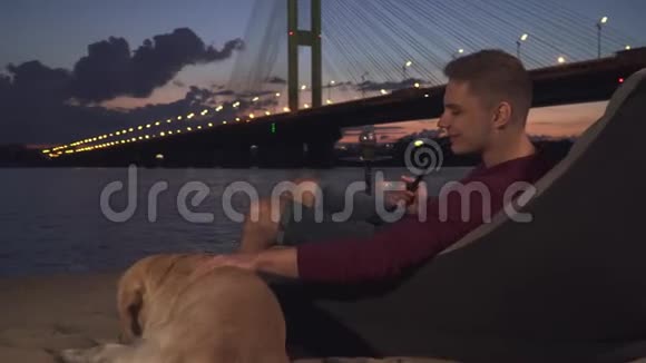 帅哥和一只狗坐在沙滩上抽烟视频的预览图