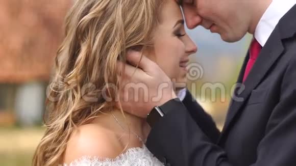 浪漫的婚礼肖像英俊的新郎在户外轻轻地亲吻他迷人的微笑新娘视频的预览图