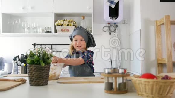 穿围裙的快乐小女孩在厨房里擀面团视频的预览图