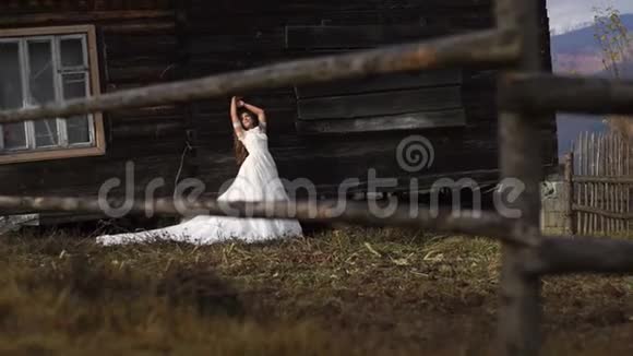 美丽美丽的新娘在村庄的木制乡村房子附近摆姿势的完整视角视频的预览图