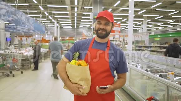 穿着红色制服的帅哥站在超市里手里拿着纸袋微笑视频的预览图