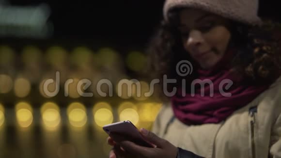 年轻女性看社交媒体新闻在户外等朋友视频的预览图