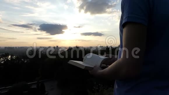 一个年轻的学生坐在草坪上看一本书日落时分在索洛莫视频的预览图
