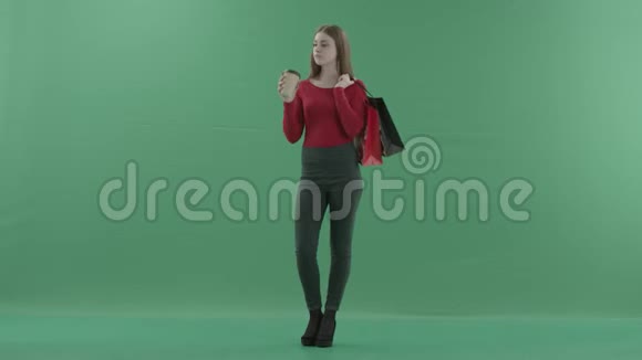 穿着休闲服的漂亮女人正拿着购物袋喝着咖啡或茶她站在工作室里视频的预览图