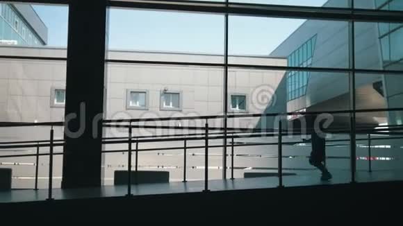 母亲和小女儿的剪影在大窗户的背景下走下机场的大门视频的预览图