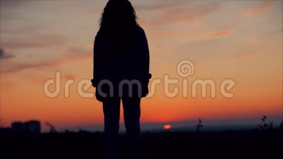 年轻的女人看着夕阳的天空成功的女孩思考大自然中的生活享受大自然的风景视频的预览图