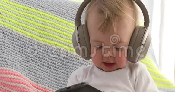 婴儿听耳机拿着智能手机视频的预览图