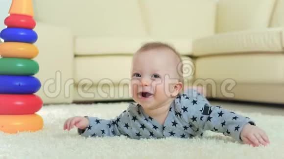 甜甜的小宝宝在家里白色地毯上玩玩具家里地板上躺着一个玩具的小男孩视频的预览图