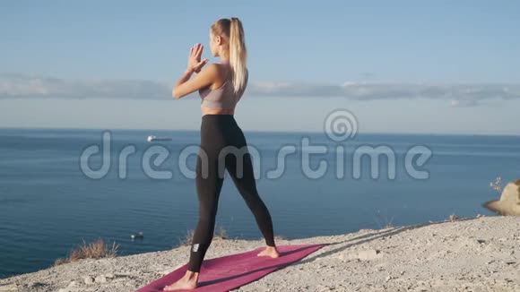 女人在山顶做瑜伽运动在背景上做海洋慢动作视频的预览图