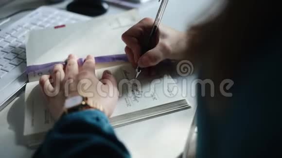 一个年轻女人用日历写她的计划的近景她的左手有一块金表视频的预览图
