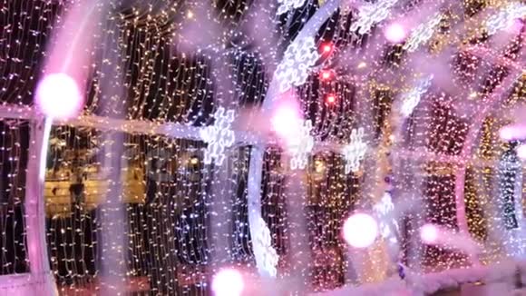 彩色灯泡和引导雪花在光隧道圣诞街饰新年准备视频的预览图