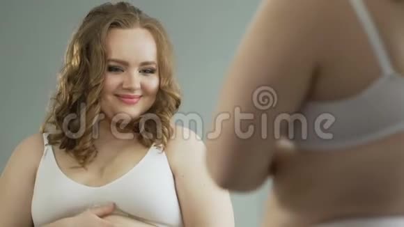体重超标的女性在镜子里欣赏自己的曲线只穿内衣视频的预览图